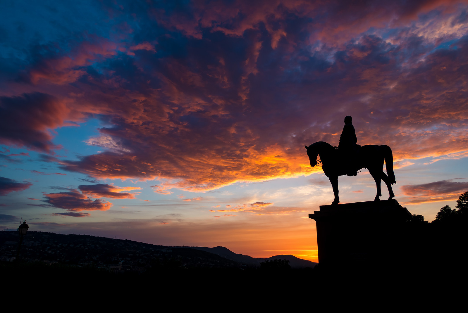 dramatic sunset behind horse statue of Görgey Artúr